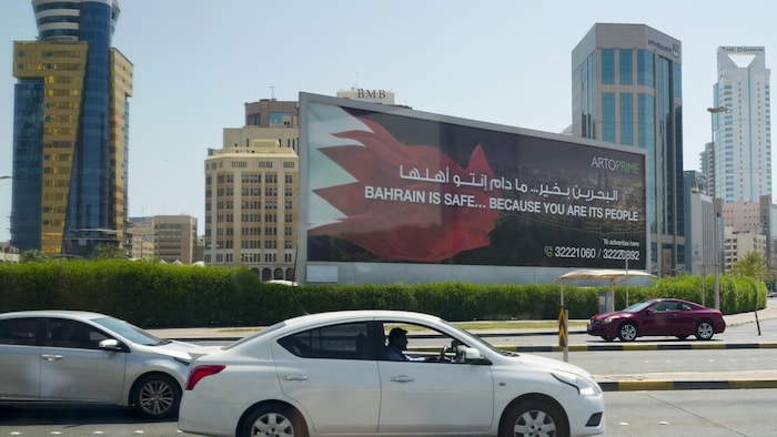 Des voitures circulent devant un panneau publicitaire.