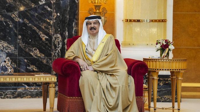Hamad ben Isa Al Khalifa est assis sur un fauteuil dans une salle.