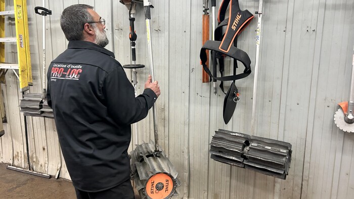Un homme prend un balai mécanique dans un garage.