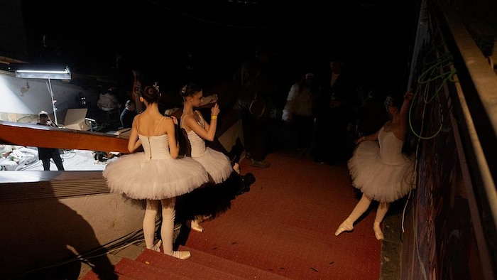 Trois jeunes ballerines attendent en coulisses. 