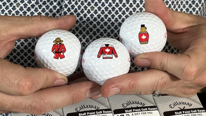 Trois balles de golf ornées de symboles canadiens.