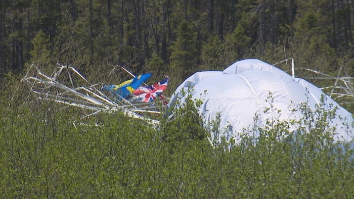 Un drapeau Union-Jack s'accroche à la structure détruite d'un ballon à hydrogène écrasé dans la broussaille.