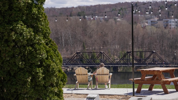 Plan large sur deux gens de dos sur des chaises en extérieur au parc.