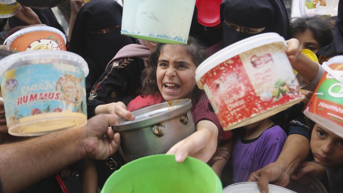 نساء وأطفال فلسطينيون يحاولون الحصول على بعض الطعام في رفح يوم الاثنين.