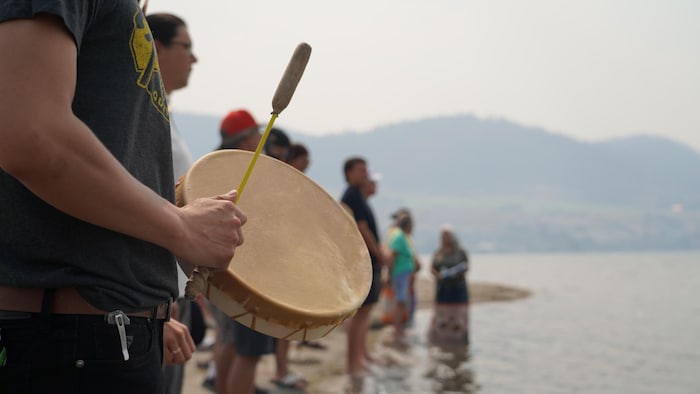 Des gens rassemblés pour une cérémonie sur le bord de l'eau.