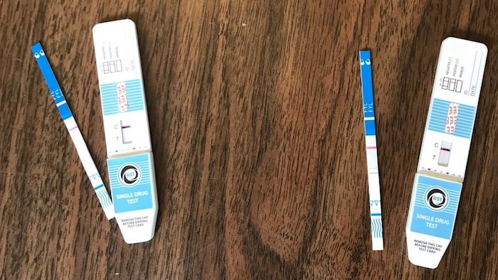 On voit deux tests qui affichent positifs, posés sur une table en bois.