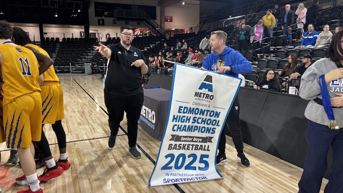 Ronald Déry tient la bannière de championnat dans ses mains lors de la remise des prix.