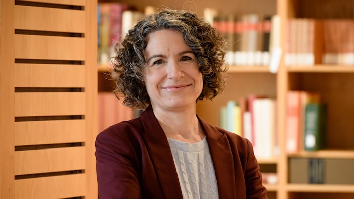 Mireille Laforce prend la airs devant un rayon de bibliothèque.