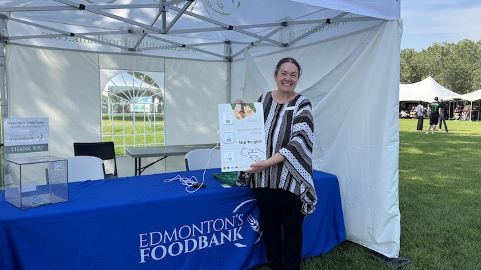 Tamisan Bencz-Knight, directrice des communications à la Banque alimentaire d’Edmonton, montre une pancarte indiquant les modes de paiement sans contact acceptés.
