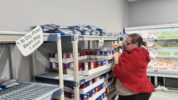 Trazy Collins place    �des conserves sur les étagères de la banque alimentaire.