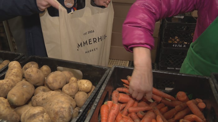 Une bénévole de la banque alimentaire Fort York à Toronto remplit le sac d'un client. 