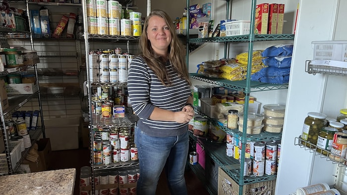 Une femme se dresse devant des établis remplis de provisions.