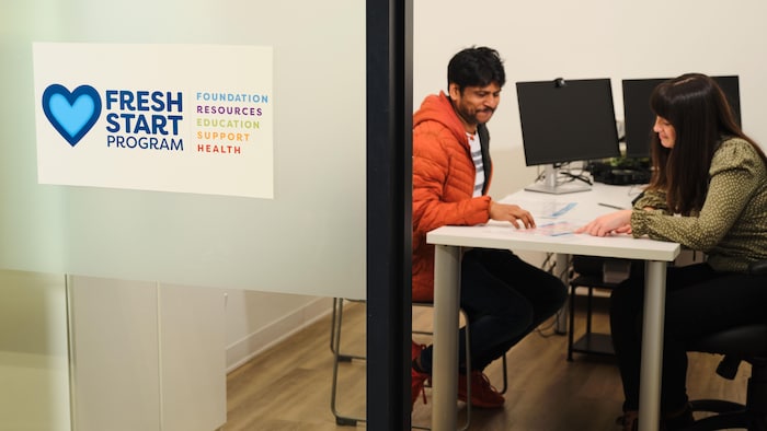 Un client rencontre une employée de la Banque alimentaire dans un bureau vitré.
