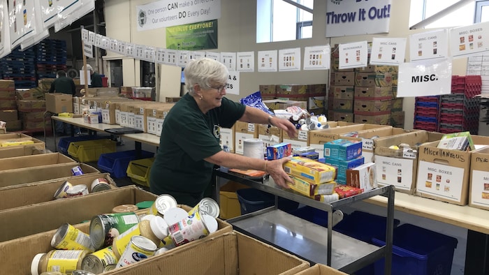 عاملة متطوعة تقوم بفرز المواد الغذائية في مستودع بنكٍ للطعام في مدينة سادبوري في مقاطعة أونتاريو.