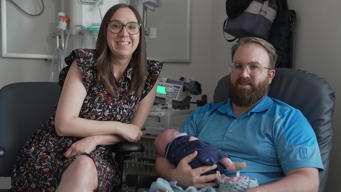 Tiffany Raymond et Sébastien Dupuis, bébé dans les bras, regardent la caméra en souriant.