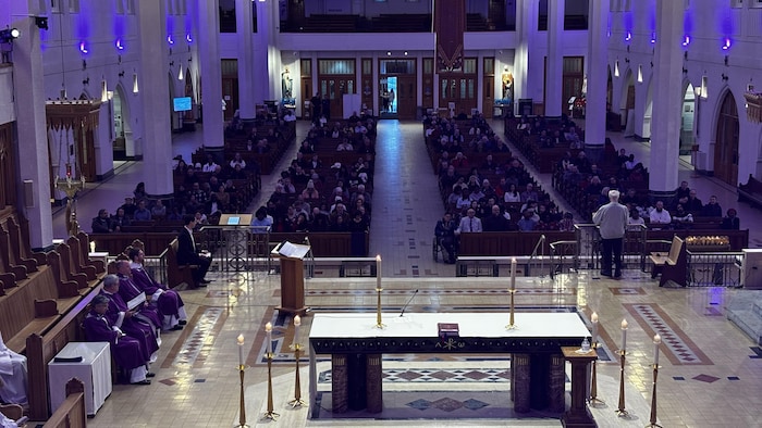 L'intérieur de la basilique-cathédrale Saint-Michel avec plusieurs personnes assis sur les bancs.