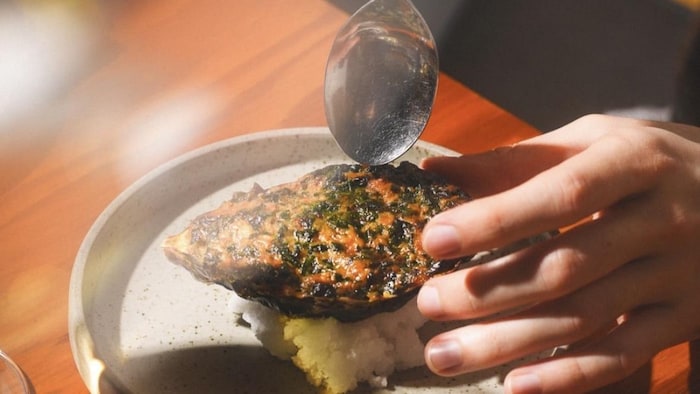 Un chef dépose avec une cuillère la dernière pièce de son plat.