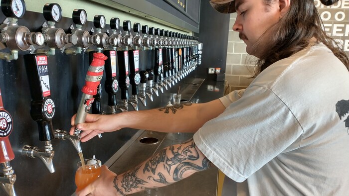 Un employé de la brasserie Parallel 49 remplit un verre de bière.