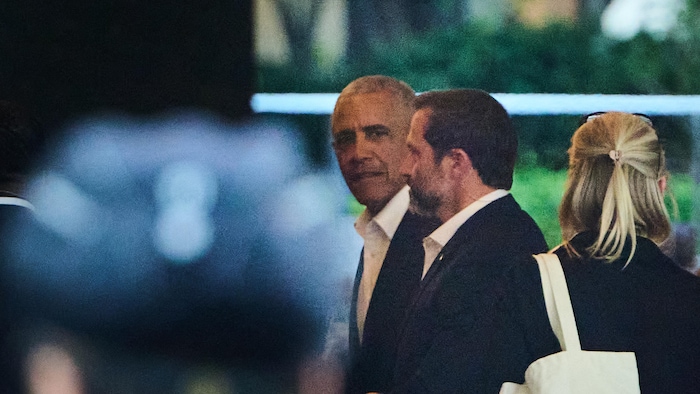 Barack Obama marche avec deux personnes.