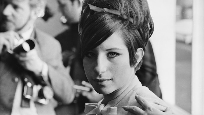La femme regarde l'objectif avec intensité, avec un autre photographe en arrière-plan.