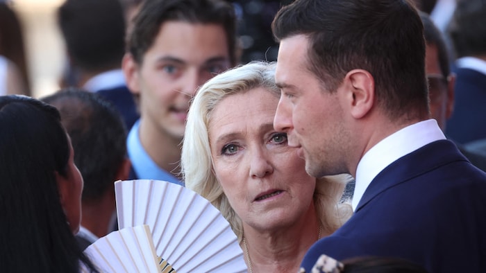 Marine Le Pen (à gauche sur la photo) observe la scène aux côtés de Jordan Bardella.