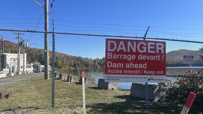 Une affiche indique un danger, près d'un cours d'eau.