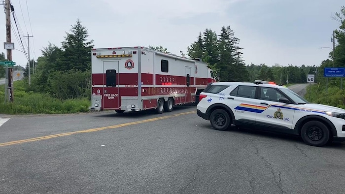 Un camion de pompiers et un véhicule de la GRC sont garés en travers de la route.