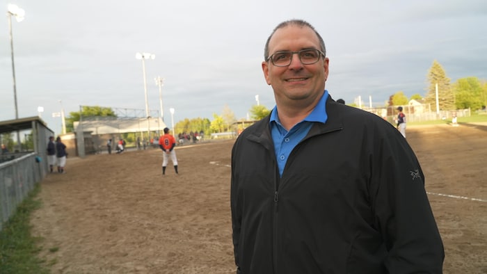 Un homme devant un terrain de baseball.