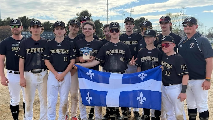 Des joueurs de baseball tiennent le drapeau du Québec.