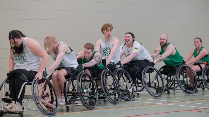 Les athlètes de basketball en fauteuil roulant font la file avec l'entraîneur, Reid Richard.
