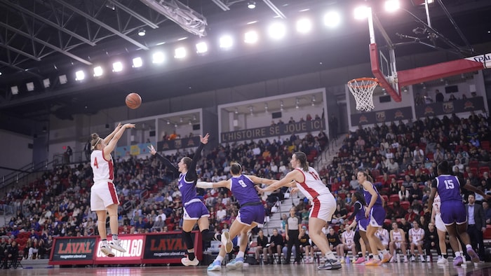 Une joueuse du Rouge et Or tire. Une autre tente d'intercepter le ballon.