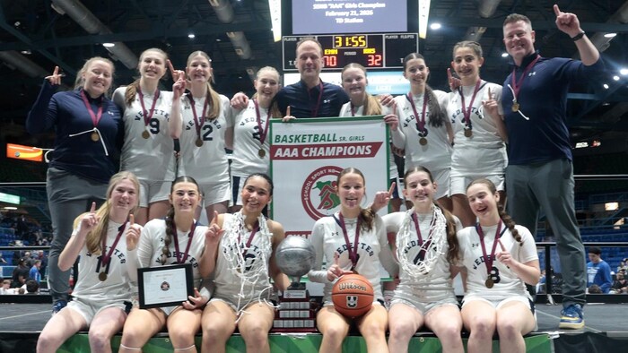 Une équipe de basketball avec un trophée et une bannière de championne.