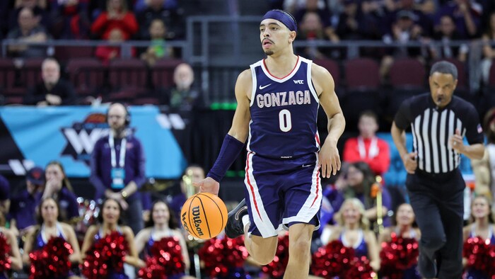 Un basketteur dribble le ballon sur le parquet pendant un match.