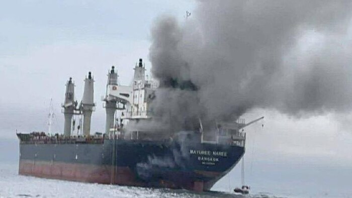 De la fumée noire et grise s'échappe d'un bateau dans le détroit d'Ormuz, en Iran. 