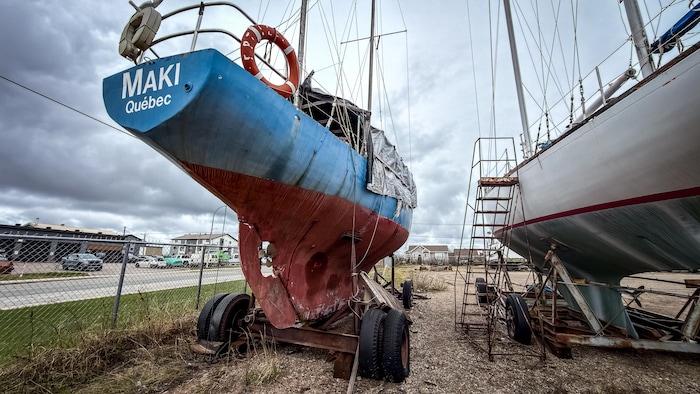 Un bateau en mauvais état est monté sur une remorque dans un parc d'hivernage. 