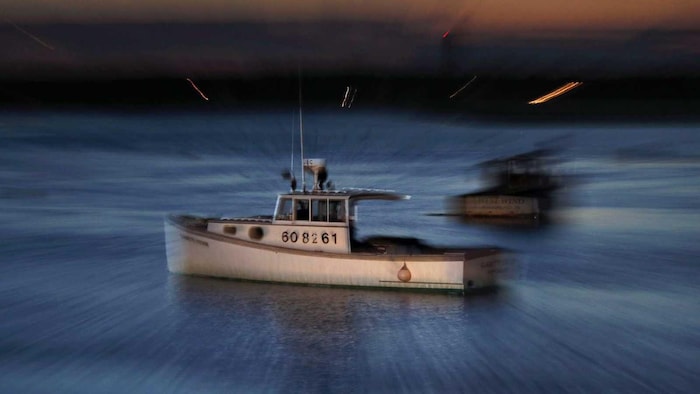 Un petit bateau de pêche sur l'eau, à la tombée de la nuit.