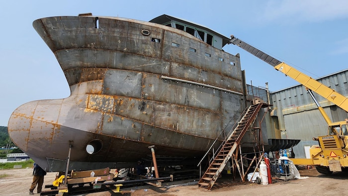 Un bateau non peint sur terre, dans un chantier naval.