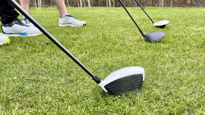 Trois bâtons de golf sont alignés sur un terrain de golf, tenus par des joueurs.
