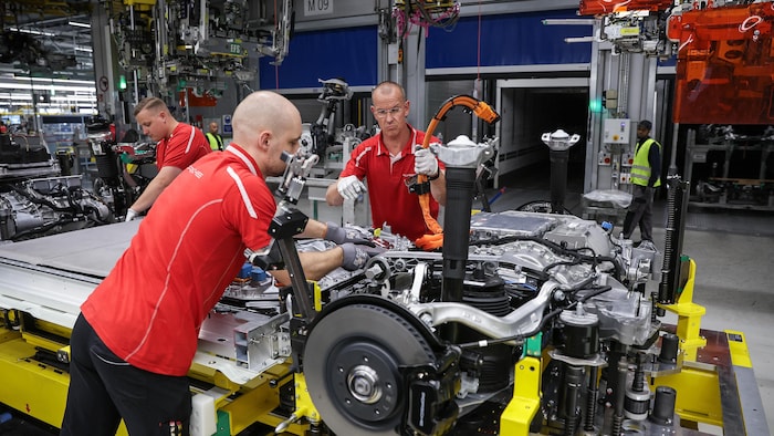 Des employés du constructeur automobile allemand Porsche travaillent sur le bloc-batterie et sur le châssis d'un nouveau modèle de voiture. 