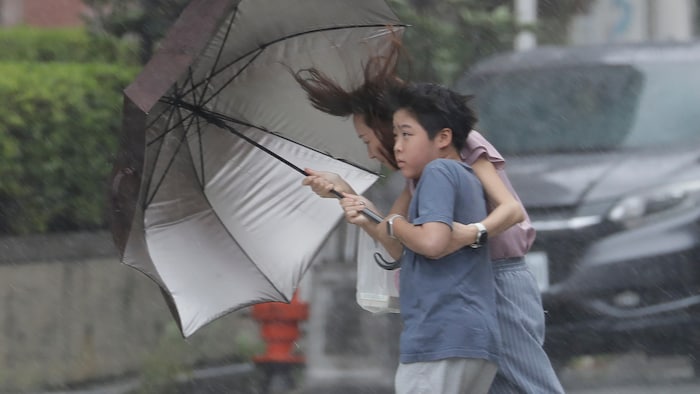 Des personnes se débrouillent avec leurs parapluies sous la pluie provoquée par le typhon Bavi à Taichung, à Taïwan, le samedi 11 juillet 2026.
