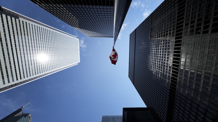 Un drapeau du Canada vu suspendu entre des édifices à Bay Street, à Toronto.