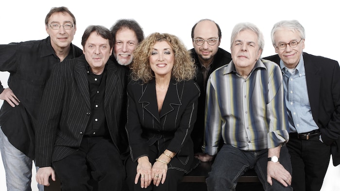 Michel Hinton, Réal Desrosiers, Pierre Bertrand, Marie Michèle Derosiers, Michel Rivard, Pierre Huet et Robert Léger sourient en regardant droit devant eux.
