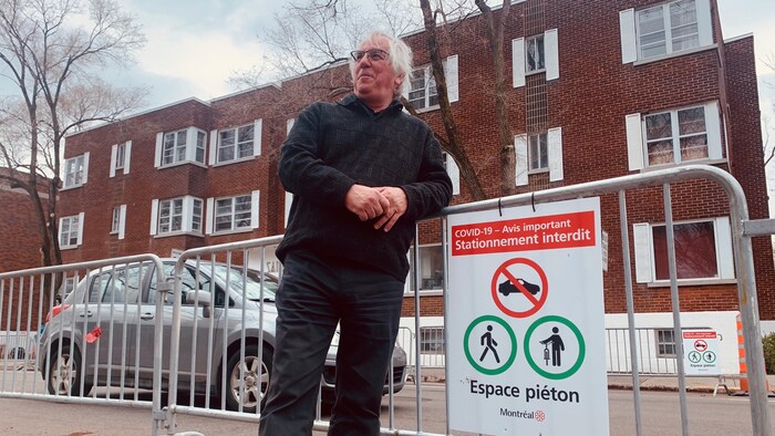 L'urbaniste est appuyé sur une clôture temporaire.