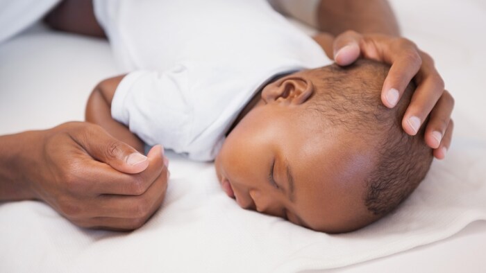 Un bébé dort, couché sur le ventre.