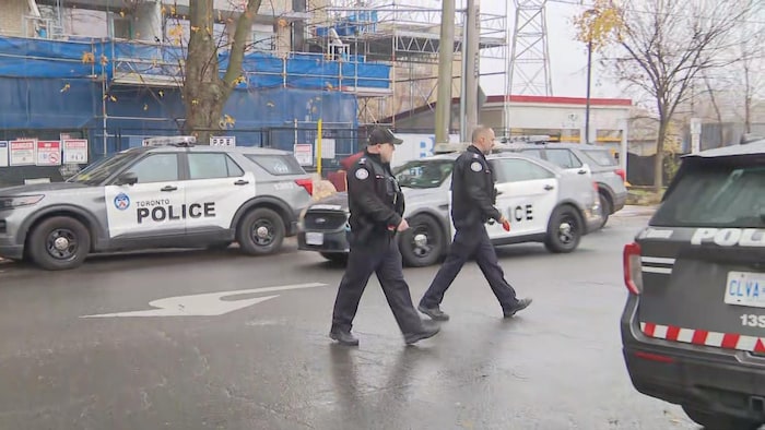 Des agents traversent la rue entre des autopatrouilles.