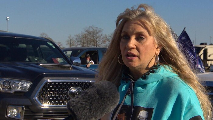 A woman being interviewed in a parking lot.