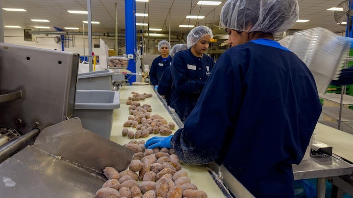 Des travailleurs dans une usine de beignes.