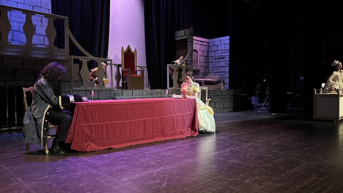 Une table drapée de rouge avec des personnes assis en train d'y prendre un repas.