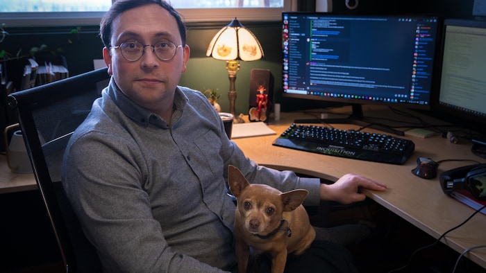 Ben Gelinas assis à son bureau avec son chien, en février 2024.