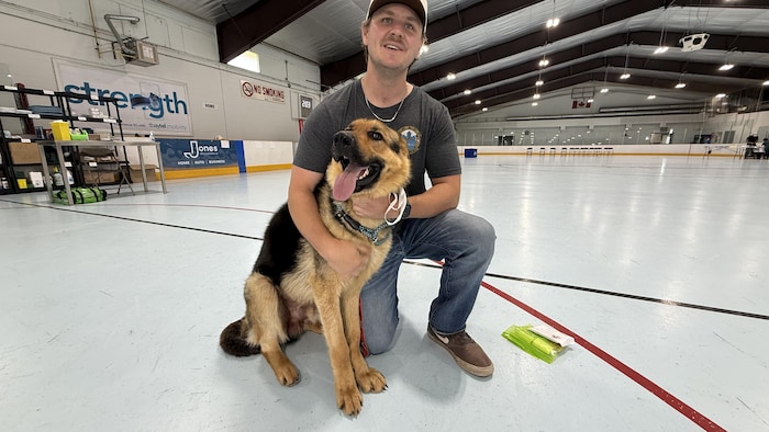 Portrait de Ben Whitburn avec un genou au sol, tenant le chien Buddy.